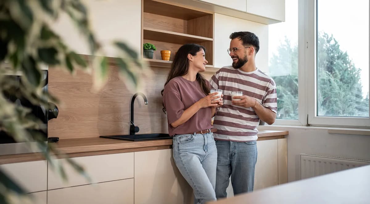 Couple talking in a bright kitchen beside a uPVC window