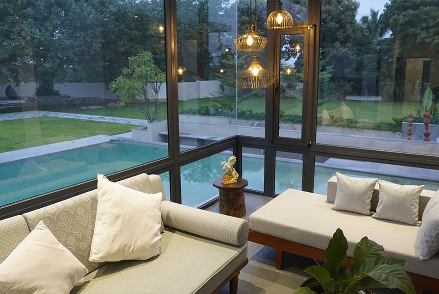 Luxury living space framed by full-height uPVC glass doors overlooking a pool at dusk